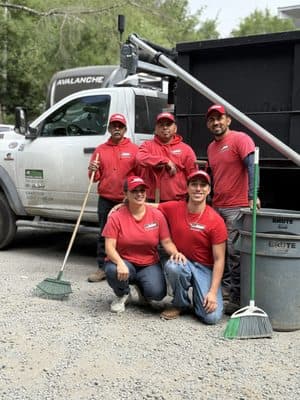 MC Junk Removal crew in red shirts with their hauling truck and cleanup tools